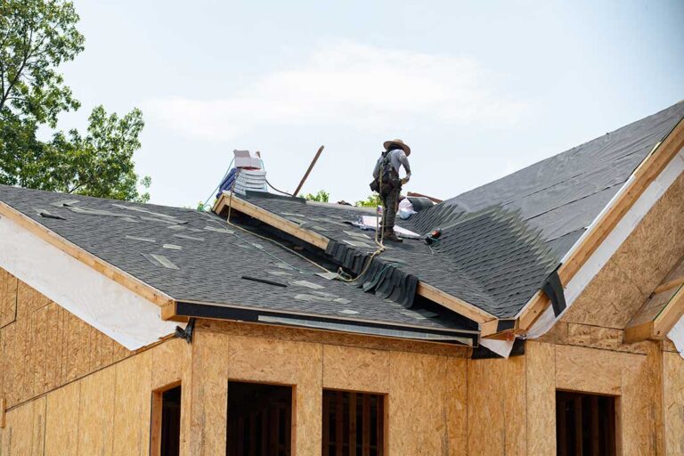 A close-up of a weathered residential roof showing sun damage and moss growth after recent rain.